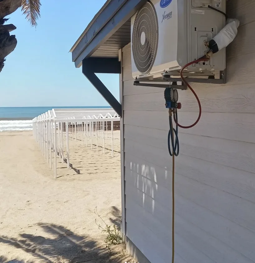 Unidad exterior de aire acondicionado instalada junto a la playa, con el mar de fondo